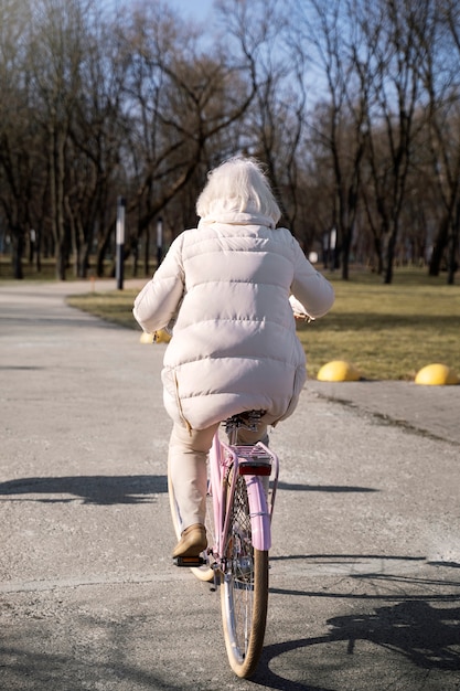 Полный снимок пожилой женщины на велосипеде на открытом воздухе