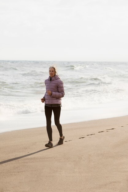 Full shot senior woman running on beach