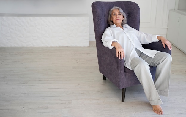 Full shot senior woman sitting on chair