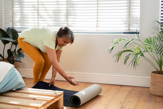 Donna senior del colpo completo con la stuoia di yoga