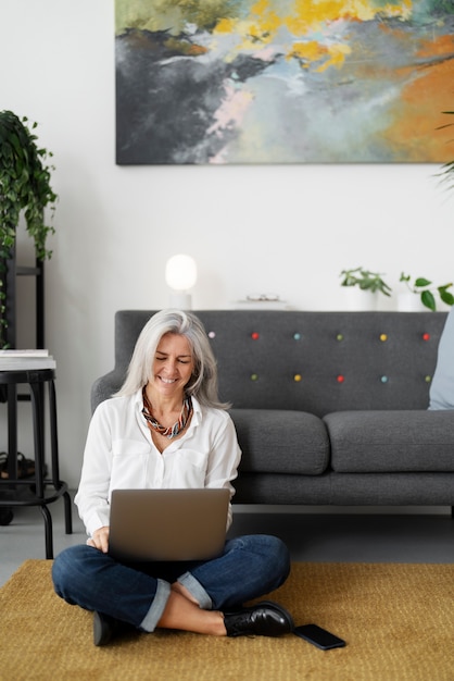 Full shot senior woman working on laptop at home