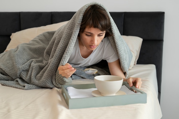 Free photo full shot sick woman with soup