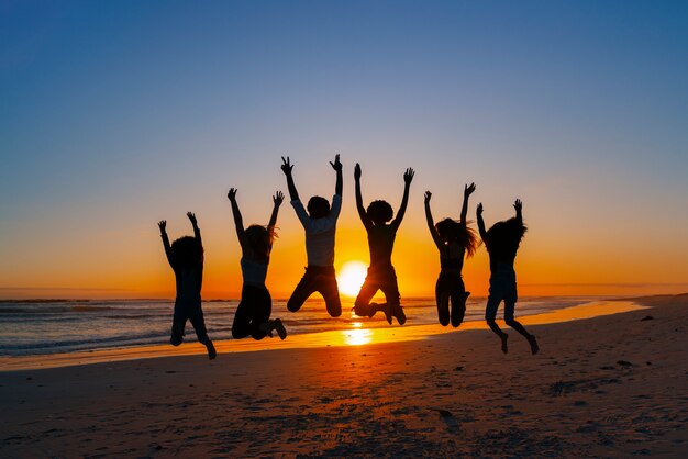 Free Photo full shot  silhouettes of people jumping at sunset