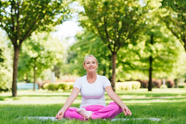 Full shot sitting woman meditating outdoors