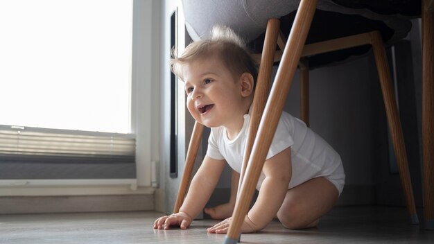 Full shot smiley baby under chair