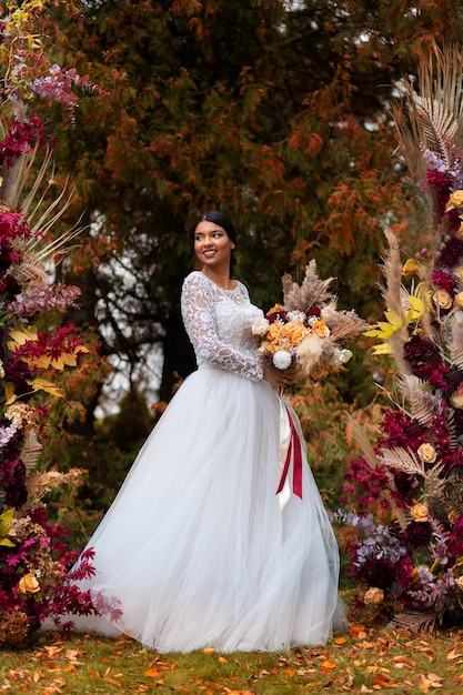 花でポーズをとるフルショットのスマイリー花嫁