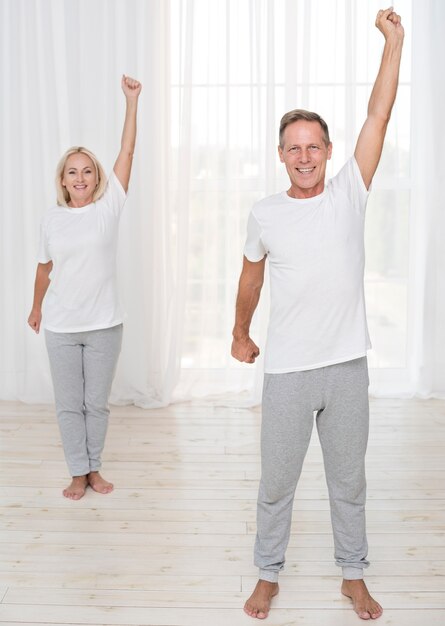 Full shot smiley couple exercising together