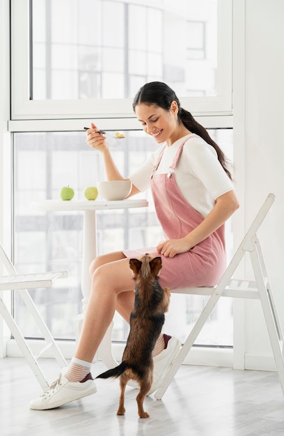 Foto gratuita ragazza piena di smiley del colpo che mangia vicino al cane