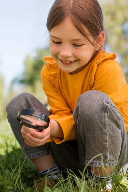 Full shot smiley girl holding magnigying glass