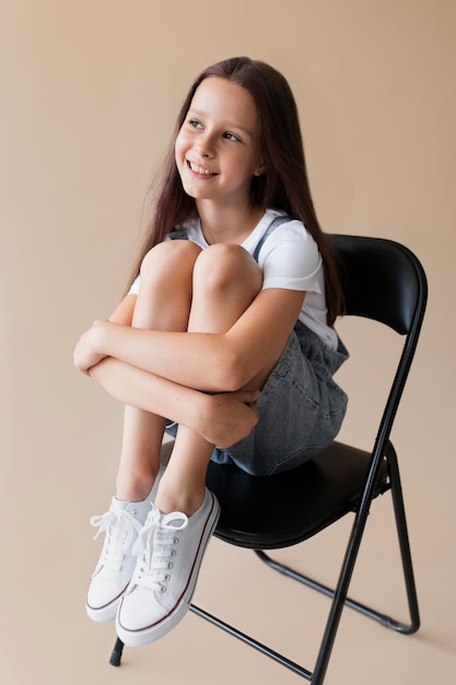 Full shot smiley girl sitting on chair