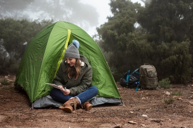 텐트 근처에 앉아 전체 샷 웃는 소녀
