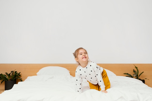 Free photo full shot smiley girl standing on bed