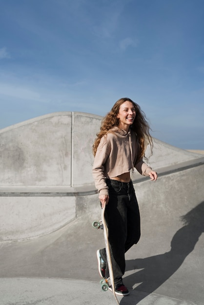 Foto gratuita ragazza sorridente a tutto campo con lo skateboard