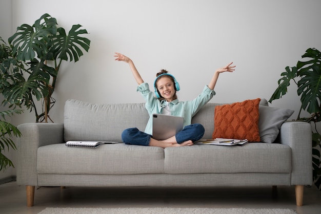 Free photo full shot smiley girl with tablet and headphones