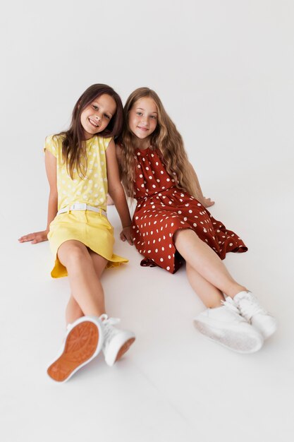 Full shot smiley girls sitting together in studio