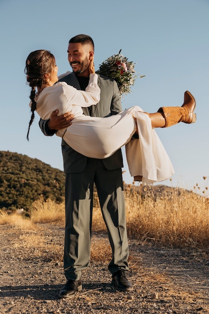 Foto gratuita sposo sorridente del colpo pieno che tiene la sposa