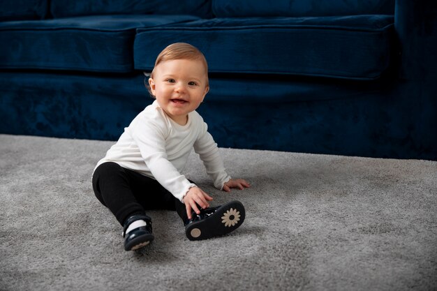 Full shot smiley kid sitting on carpet