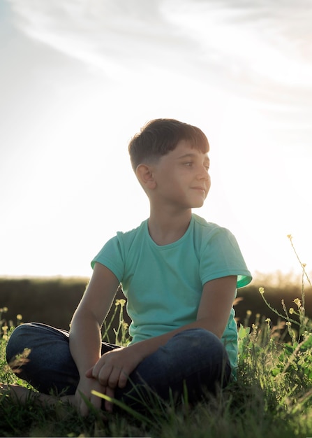 Full shot smiley kid sitting on grass