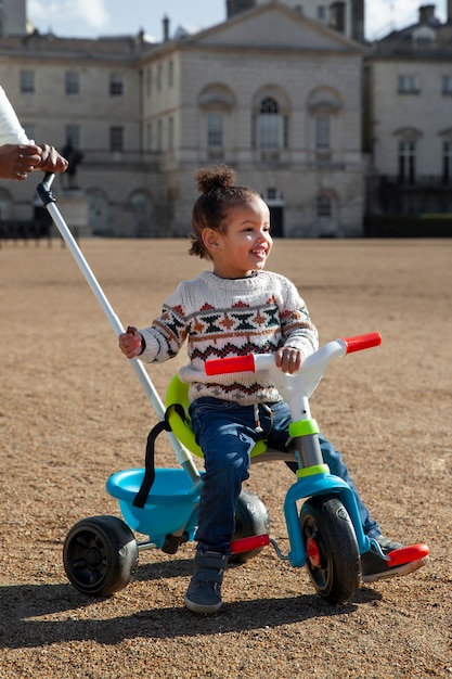 Full shot smiley kid sitting on tricycle