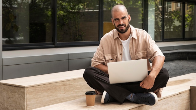 Foto gratuita computer portatile della holding dell'uomo di smiley del colpo pieno