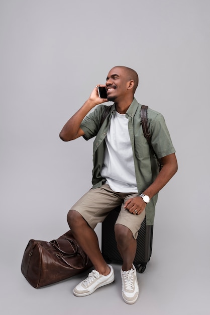 Full shot smiley man sitting on baggage