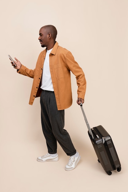 Free photo full shot smiley man with baggage and smartphone