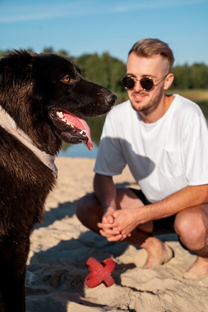 ビーチで犬と一緒にフルショットのスマイリー男