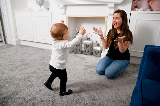 Full shot smiley mother and kid at home