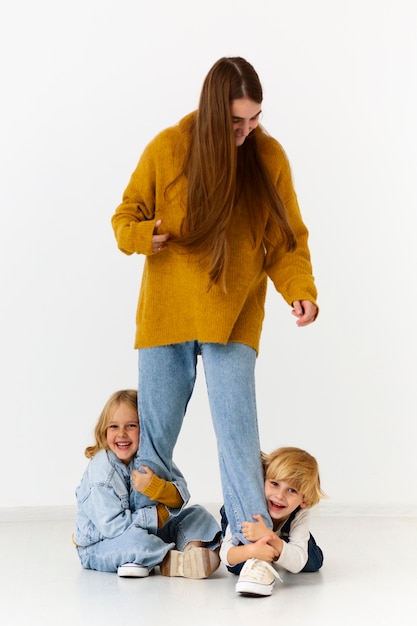 Free photo full shot smiley mother and kids in studio