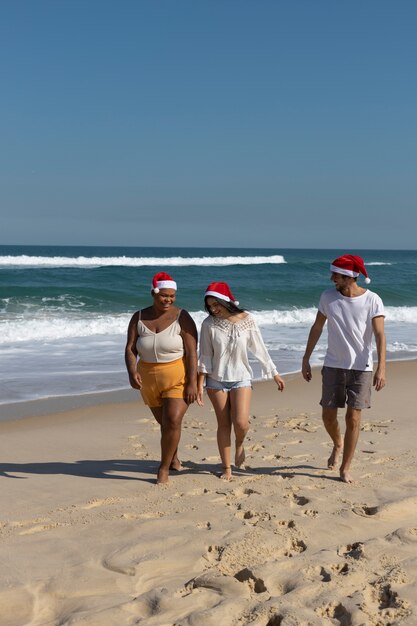 Foto gratuita gente sorridente del colpo pieno che cammina sulla spiaggia