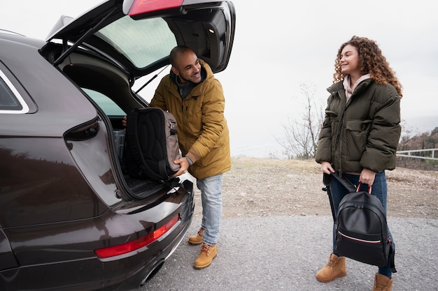 Foto gratuita persone sorridenti a tutto campo con auto