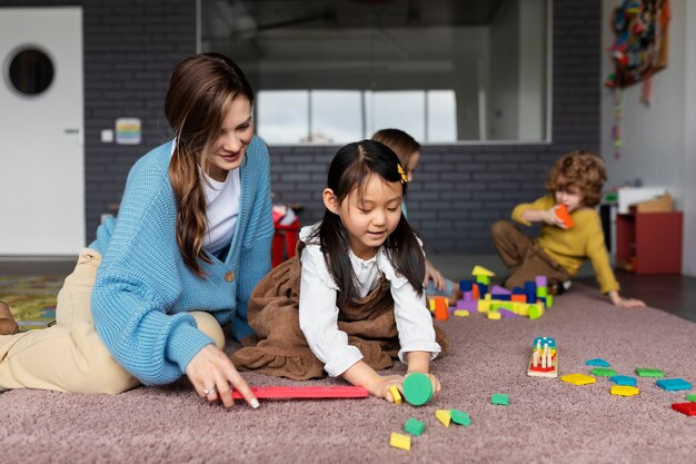 女の子が学ぶのを助けるフルショットのスマイリー教師