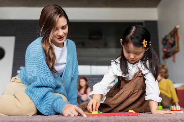 Free photo full shot smiley teacher helping kid learn