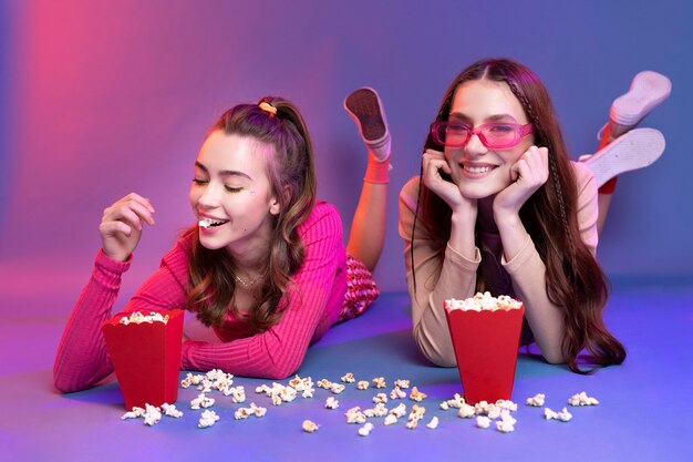 Full shot smiley teenagers eating popcorn