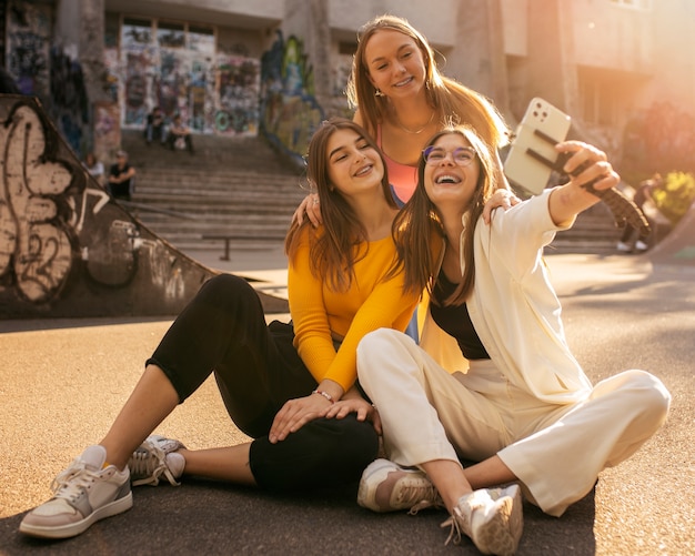 Free photo full shot smiley teens with smartphone