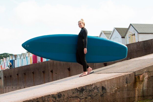 Full shot smiley woman carrying paddleboard