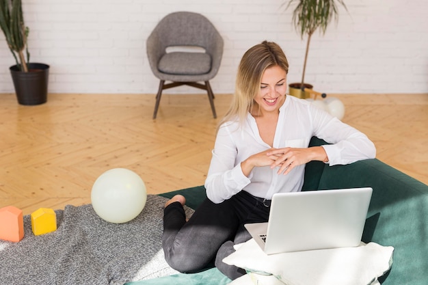 Free photo full shot smiley woman on couch working