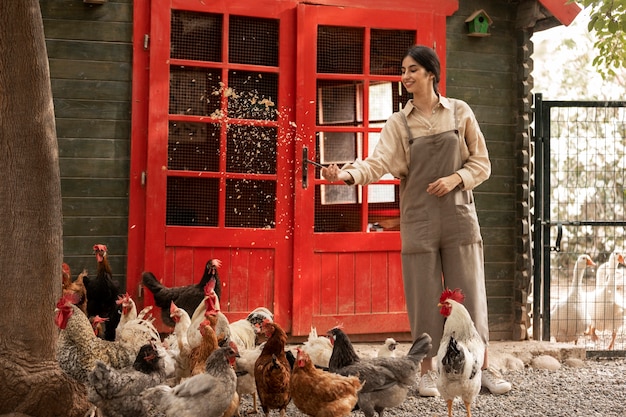 Full shot smiley woman feeding chickens