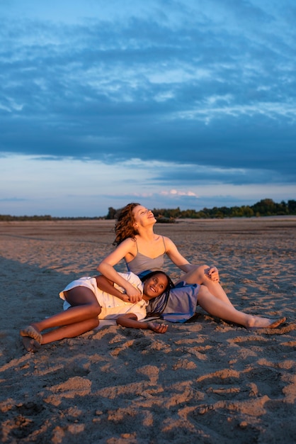 Free photo full shot smiley woman and girl on beach