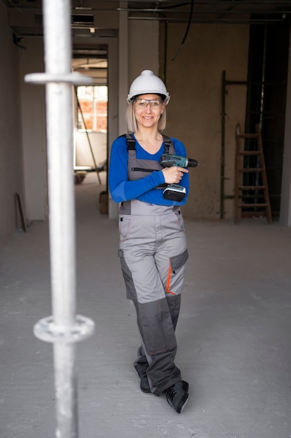 Free photo full shot smiley woman holding drill