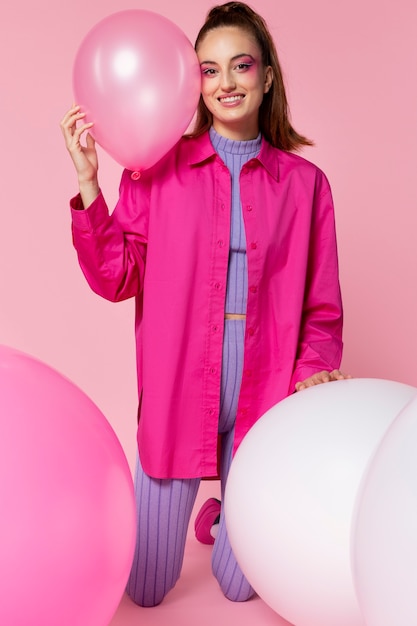 Free photo full shot smiley woman holding pink balloon