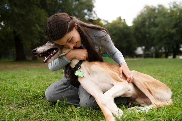 犬を抱きしめるフルショットのスマイリー女性