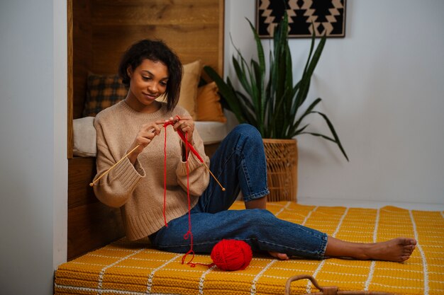 Full shot smiley woman knitting at home