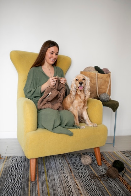 Free photo full shot smiley woman knitting at home