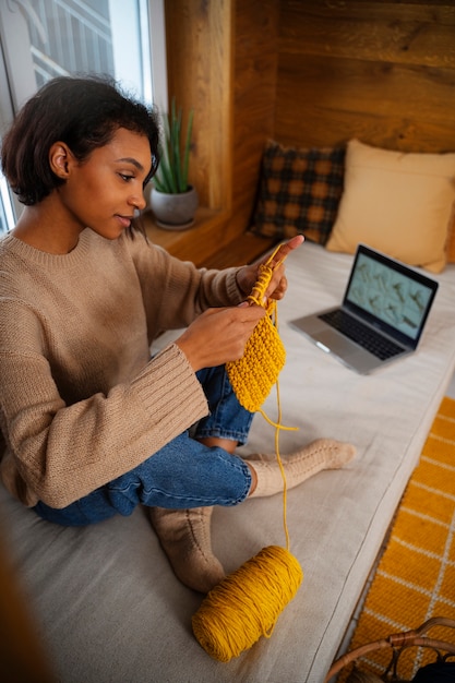 Free photo full shot smiley woman knitting indoors