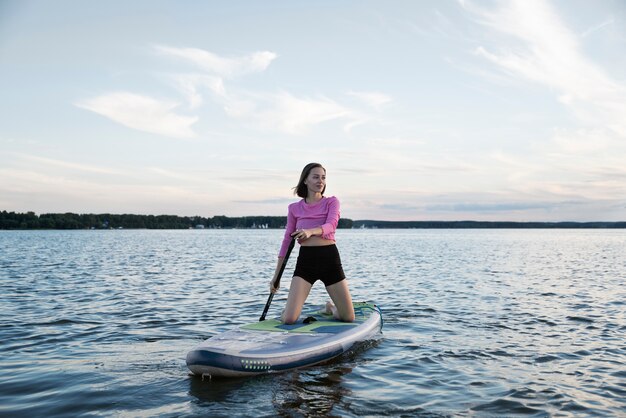 Full shot smiley woman paddleboarding