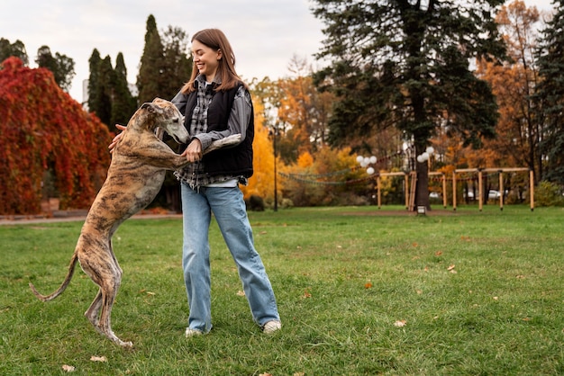 Free photo full shot smiley woman playing with dog