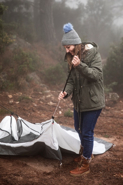 Free photo full shot smiley woman putting up tent