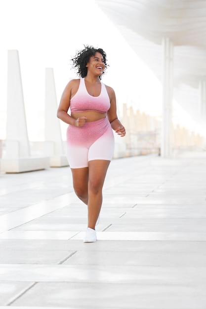 Full shot smiley woman running outdoors