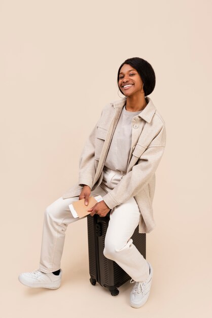 Full shot smiley woman sitting on baggage